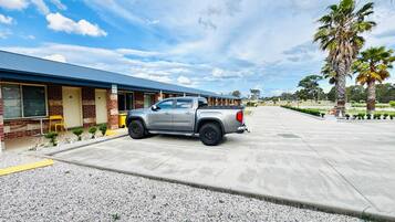 Una camioneta pickup plateada estacionada frente a un edificio con fachada de ladrillo y toldo azul.
