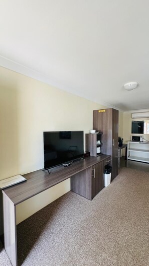 A compact living space with a kitchenette, a flat-screen TV, and a small dining area. - Marulan Motor Inn (Marulan)