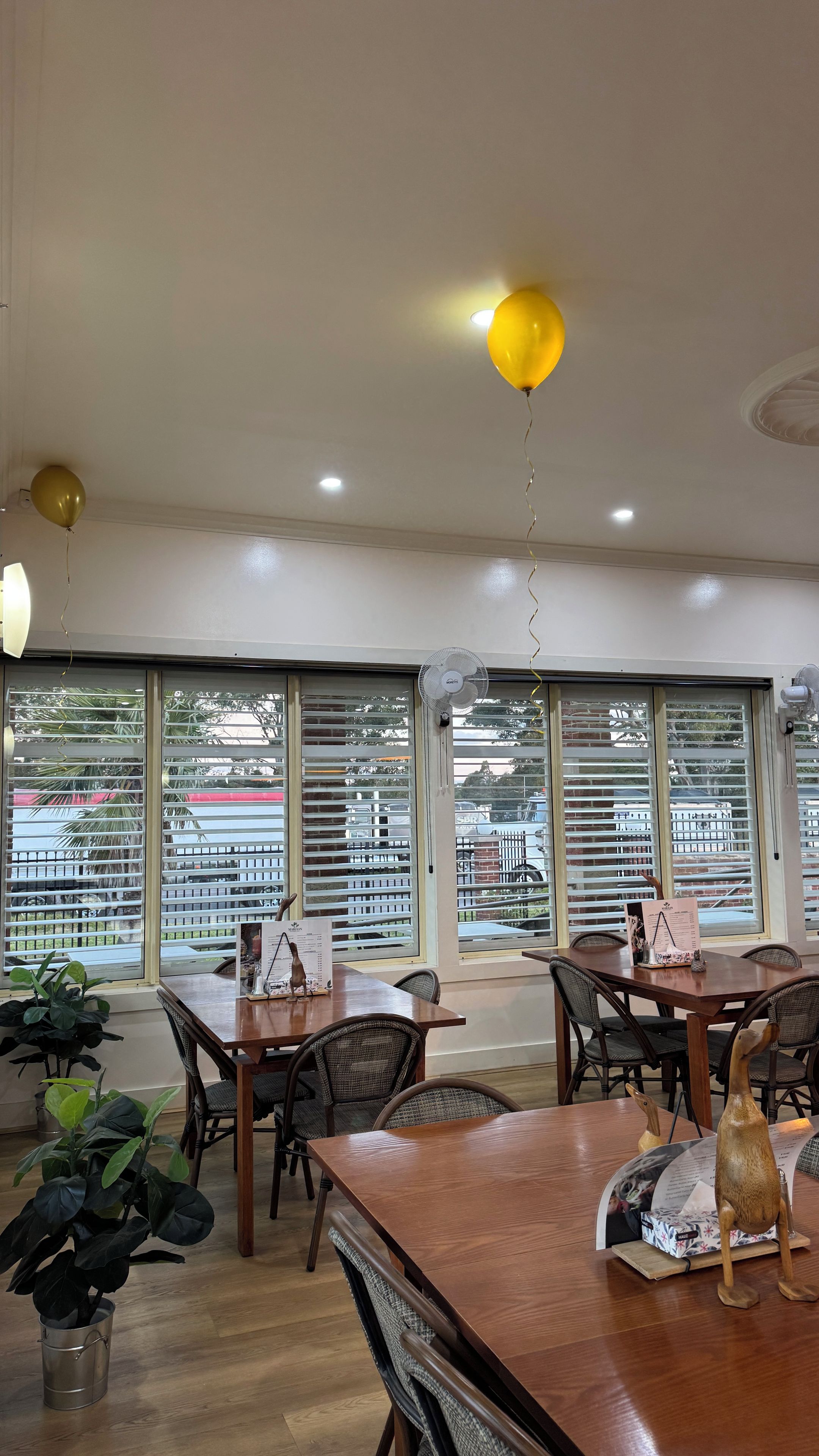 A dining area with tables, chairs, and a view through large windows.