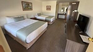 Une chambre d’hôtel avec deux lits, une télévision, un bureau et un miroir.