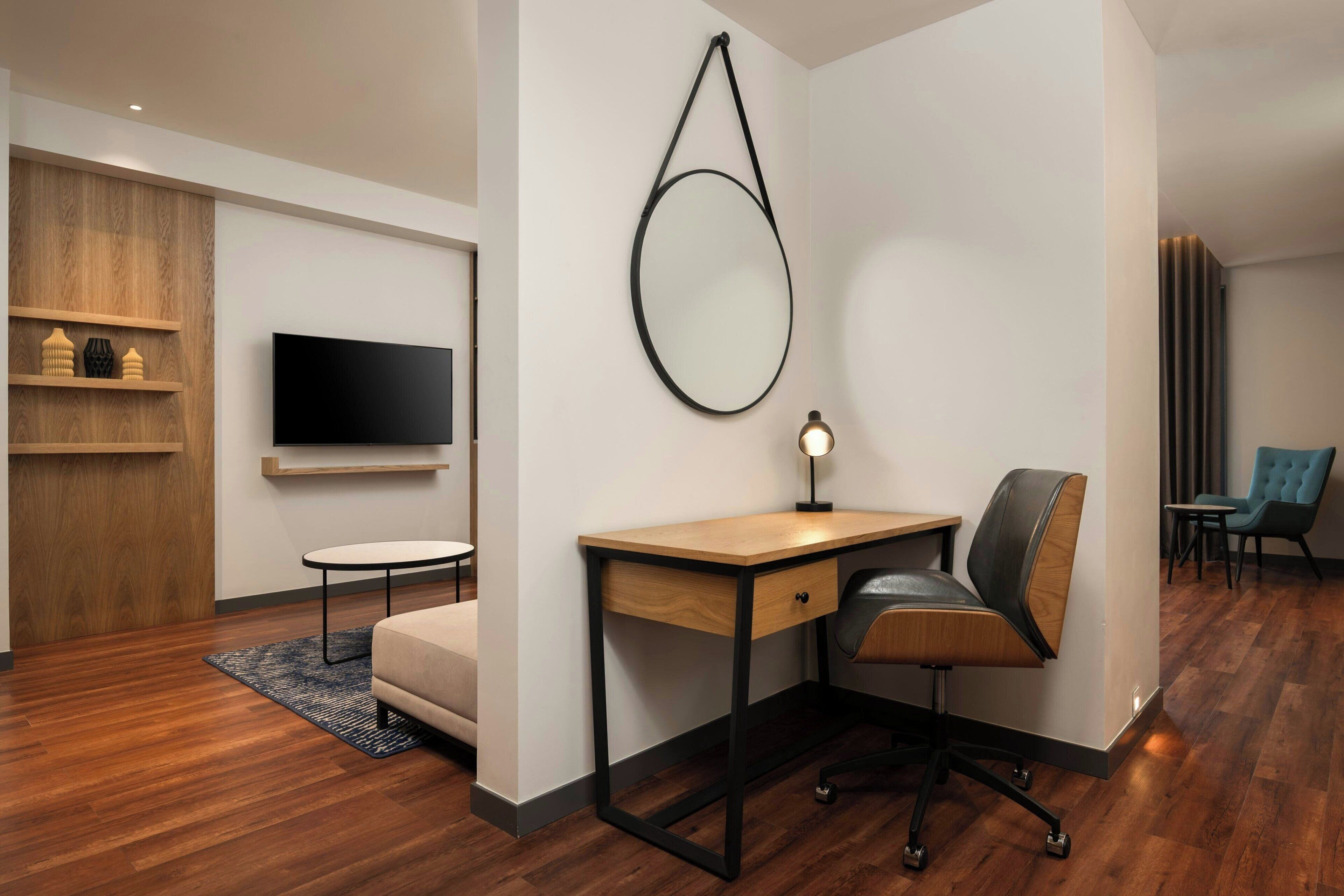 A modern office space with a desk, chair, and a round mirror on the wall.