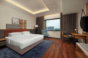 Una habitación de hotel moderna con una cama grande, un escritorio, una silla y un televisor.