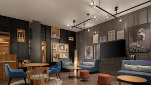 A modern lounge area with a round wooden table, blue upholstered chairs, a blue sofa, and a patterned rug. - Four Points By Sheraton Kinshasa (Kinshasa)