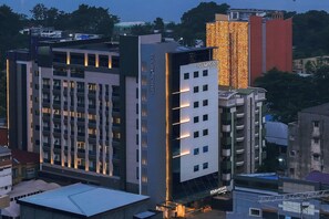 Un hotel moderno con varios pisos, un cartel vertical llamativo y una fachada bien iluminada.