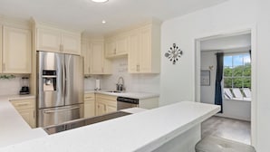 A modern kitchen with white cabinetry, stainless steel appliances, and a large island. - Luxe Coastal Escape King BD Heated pool WaterFront (Pompano Beach)