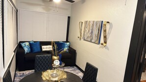A dining area with a round table, black upholstered chairs, a black sofa with blue and gold cushions, and a wall-mounted painting. - Charming and Cozy Winter Haven Oasis (Winter Haven)