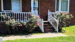 A two-story brick house with a white porch and a small staircase leading to the front door. - Beautiful 3-bedroom house with AC in Elizabeth City (Elizabeth City)