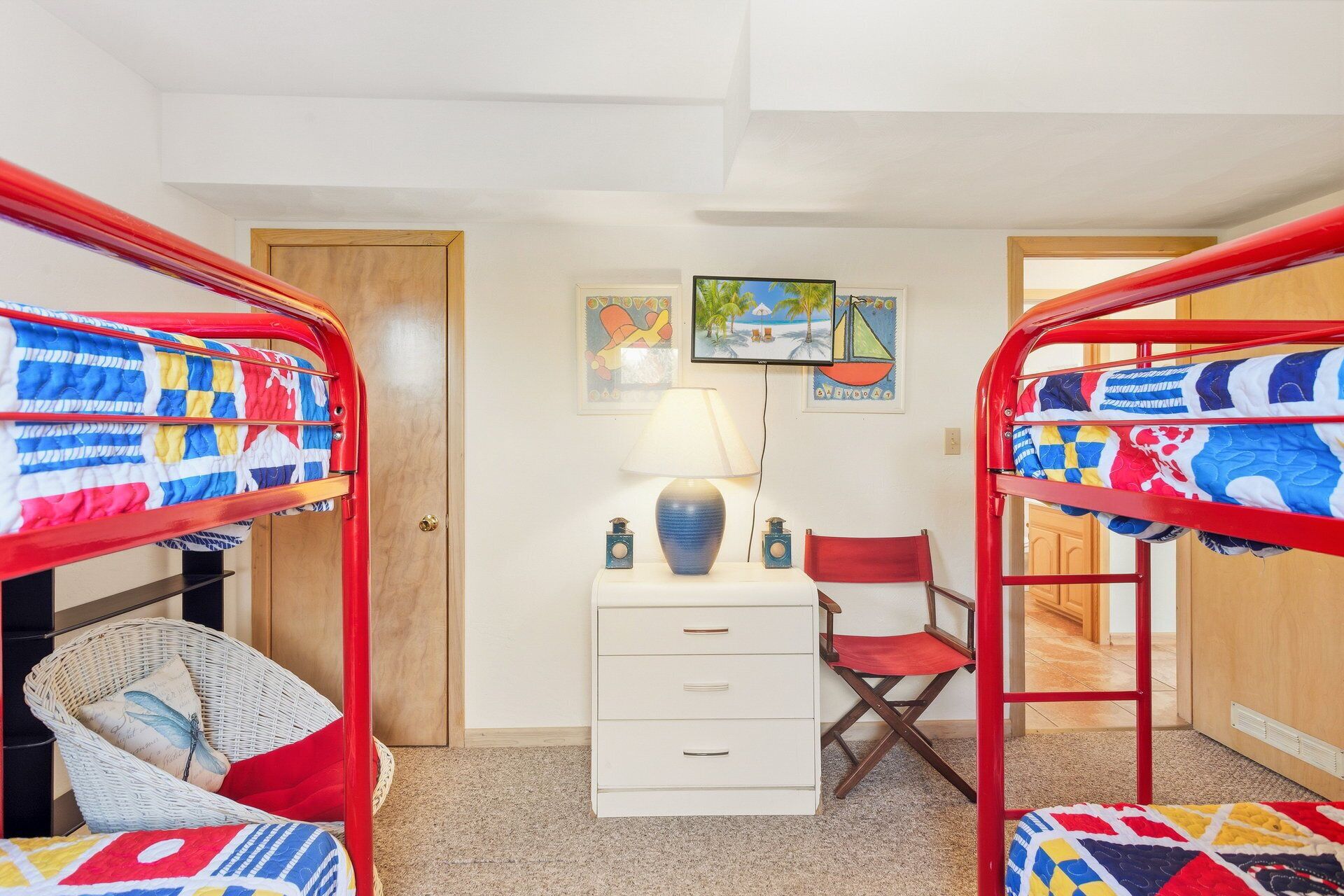 A room with bunk beds, a desk with drawers, a chair, and a lamp.