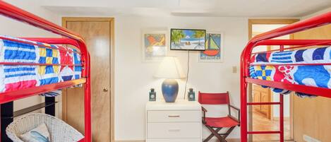 A room with bunk beds, a desk with drawers, a chair, and a lamp.