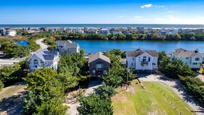 A coastal residential area with houses along a river, surrounded by greenery and a clear blue sky. - Cozy Dog-Friendly Getaway | Hot Tub & Beach Access (Waves)