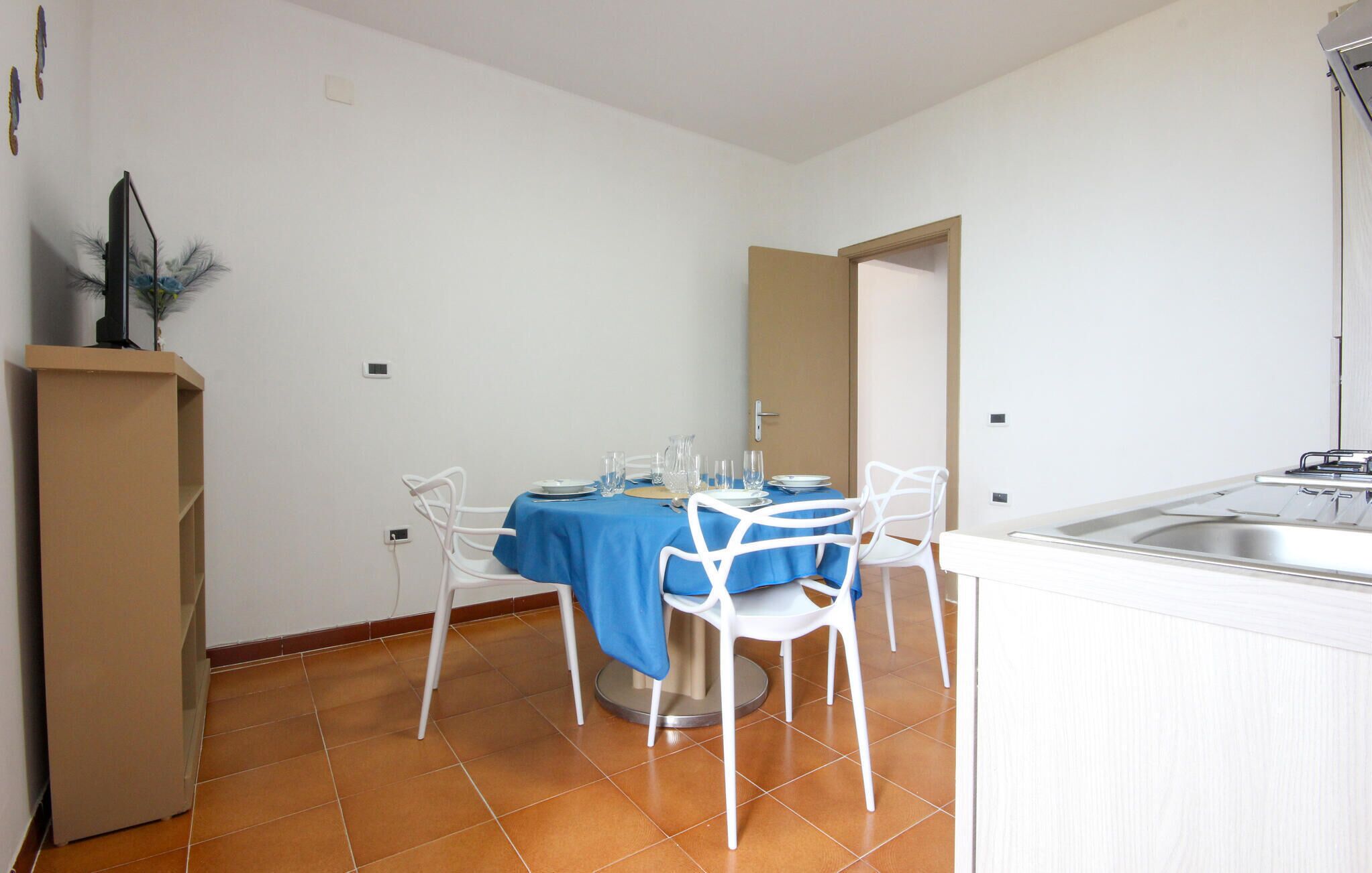 A small dining area with a table set for two, white chairs, and a blue tablecloth.