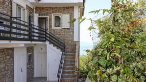 A two-story building with a stone facade, a black metal staircase, and a white door. - Lovely apartment in Castellabate (Castellabate)
