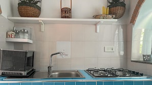 Uma cozinha com pia, fogão e prateleiras com cestos e utensílios domésticos.