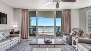 Ein geräumiges Wohnzimmer mit einem großen Schiebeglasfenster, das auf einen Balkon mit Meerblick führt.