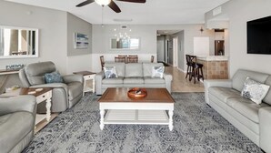 Ein Wohnzimmer mit Deckenventilator, einer Sofagarnitur, einem Couchtisch und einem gemusterten Teppich.
