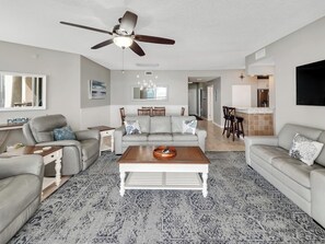 A living room with a ceiling fan, a sofa set, a coffee table, and a patterned rug. - Infinity View at Beach Colony West - Gulf-Front 3BR Condo (Navarre Beach)