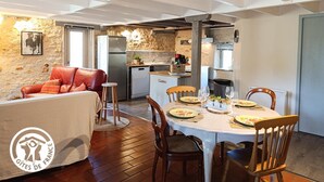 Un salon moderne avec un canapé en cuir rouge, une table à manger dressée pour quatre personnes et une cuisine en arrière-plan.