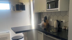 Et moderne køkken med en sort bordplade, rustfrie stålgadgetter og en backsplash med sekskantede fliser.