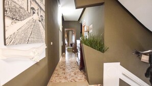 A hallway with a patterned floor, a wall-mounted plant, and a door leading to another room.