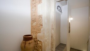 A hallway with a rustic wall, a large terracotta pot, and a door with a light fixture. - Cozy home in Solarino with WiFi (Solarino)