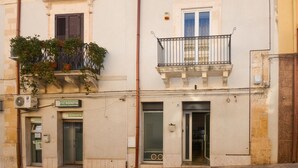 A building with a dental clinic on the ground floor, featuring a large window and a balcony with plants. - Cozy home in Solarino with WiFi (Solarino)