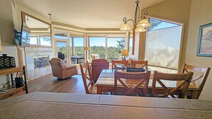 A spacious living area with a fireplace, a dining table with chairs, and a view of the outdoors. - River Village 331AB Ground Floor Condo in Bend, OR 2 Bd, 2 Ba (Bend)