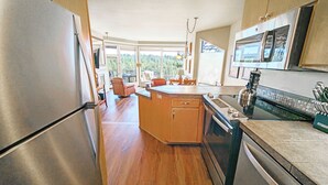 A modern kitchen with a stainless steel refrigerator, a large island with a sink, and a black stove. - River Village 331A 1 Bd, 1 Ba First Floor Condo (Bend)