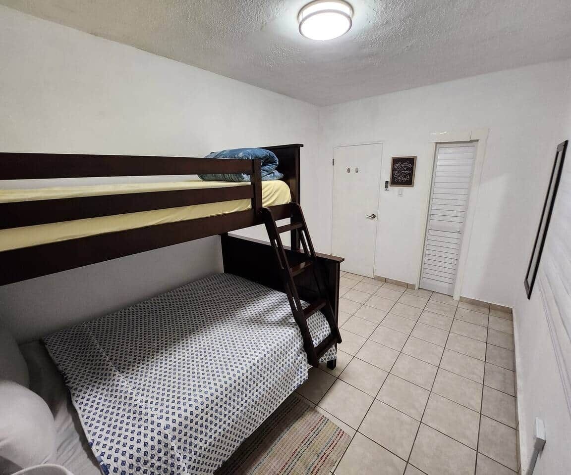A bunk bed room with a tiled floor, a door, and a framed picture on the wall.
