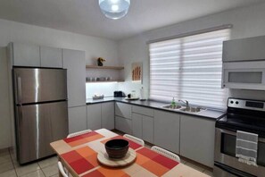 Une cuisine compacte équipée d’un réfrigérateur, d’une cuisinière, d’un four à micro-ondes et d’une table à manger avec des chaises.
