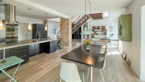 A modern kitchen with a central island, a dining area with a table and chairs, and a staircase leading to an upper level. - 2 bedroom nice home in Harpelunde (Harpelunde)