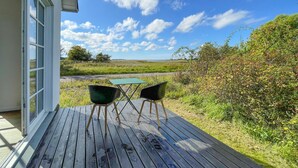 A wooden deck with two green chairs and a table, overlooking a grassy field and a road. - 2 bedroom nice home in Harpelunde (Harpelunde)