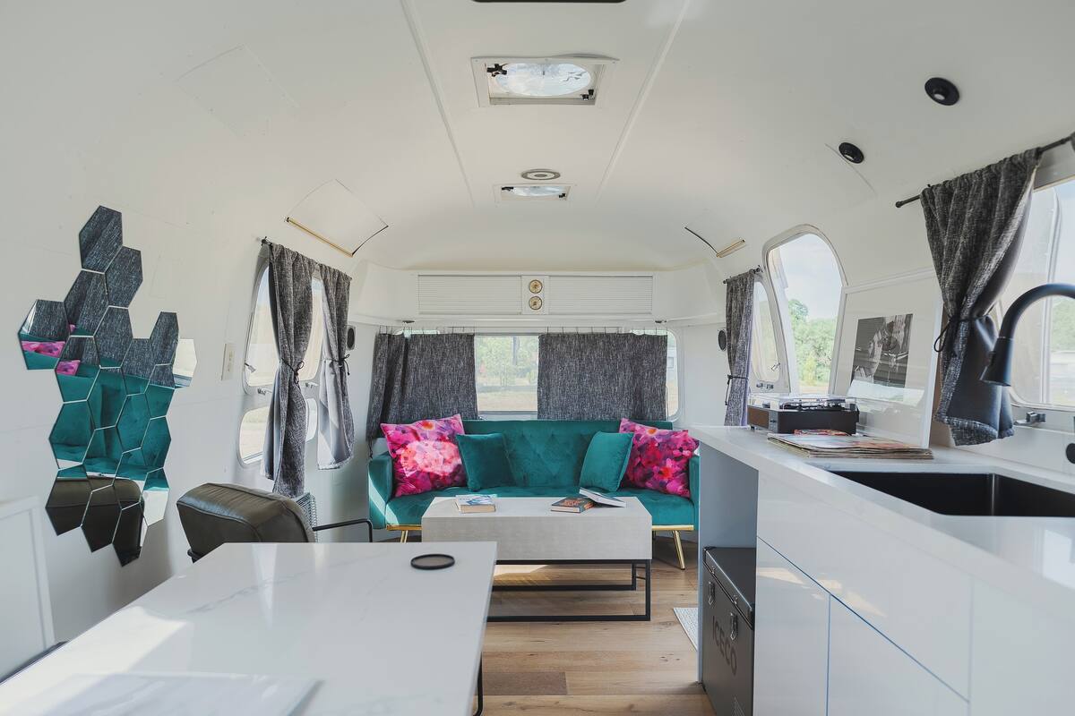 Un espace de vie compact comprenant un canapé, une petite table, un coin cuisine et une fenêtre avec des rideaux.
