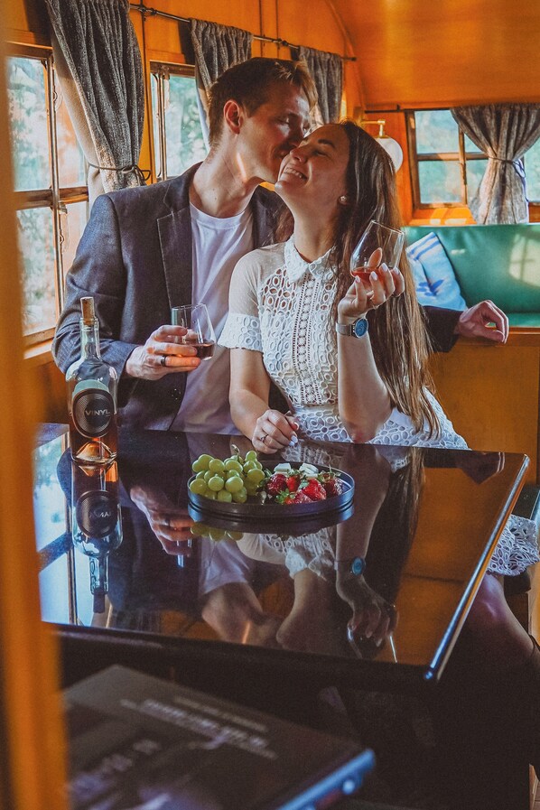 A couple seated at a table with a bottle of wine, a glass, and a bowl of grapes and strawberries. - Vinyl Vineyards  (Paso Robles)