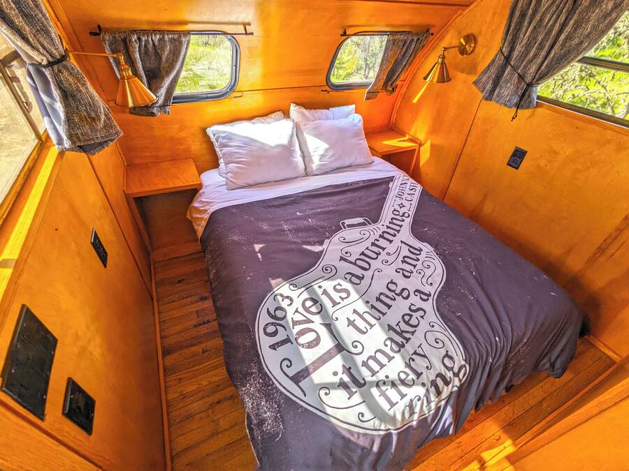 Een gezellig interieur met een bed, twee ramen en een klein tafeltje.