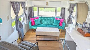 A cozy RV interior with a teal sofa, a wooden coffee table, and a compact kitchenette. - Vinyl Vineyards  (Paso Robles)