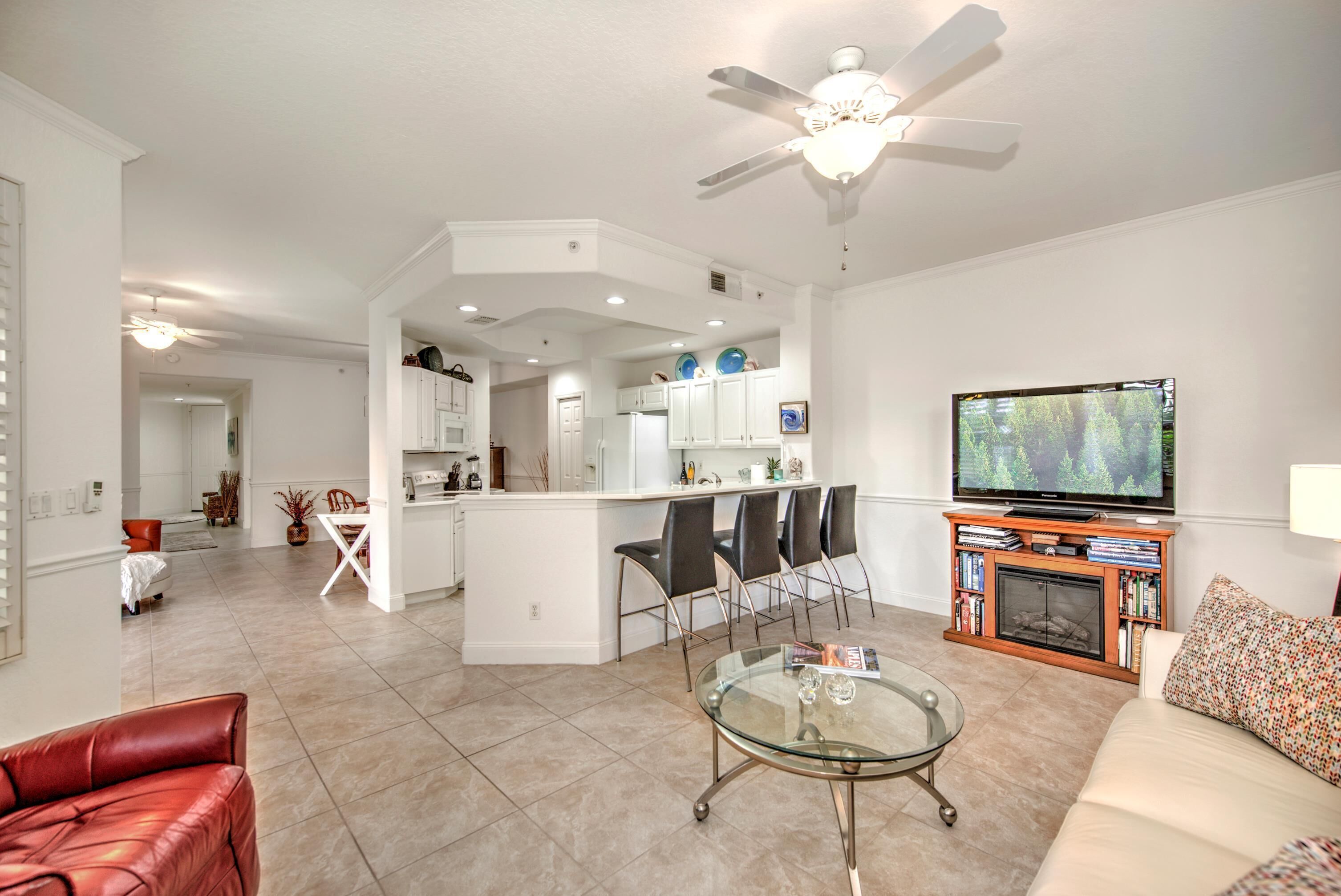A modern living room with a glass coffee table, a red leather sofa, a TV, and a fireplace.