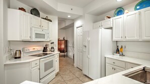 A modern kitchen with white cabinetry, a built-in oven, a microwave, and a refrigerator. - Beautiful First-floor, End Unit, Coach Home in Fiddler's Creek, Naples, FL (Naples)