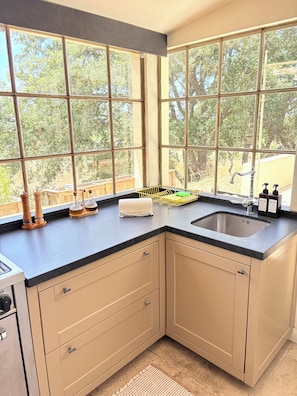 A kitchen with a large window, a sink, and a countertop with various items.