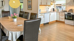 A modern kitchen with white cabinets, a stainless steel oven, and a dining area with a table set for four.