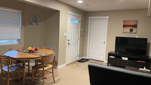 Un salon comprenant une table à manger en bois, des chaises, un téléviseur et une porte.
