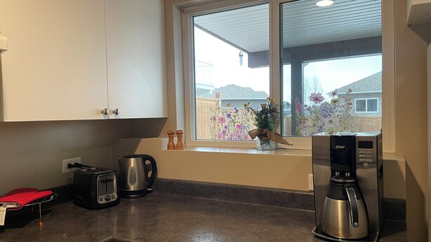 Une cuisine avec une fenêtre, un grille-pain, une bouilloire et une machine à café.
