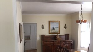 A spacious kitchen with wooden cabinets, a dining table with chairs, and a painting on the wall. - Charming Santa Barbara Cottage (Santa Barbara)