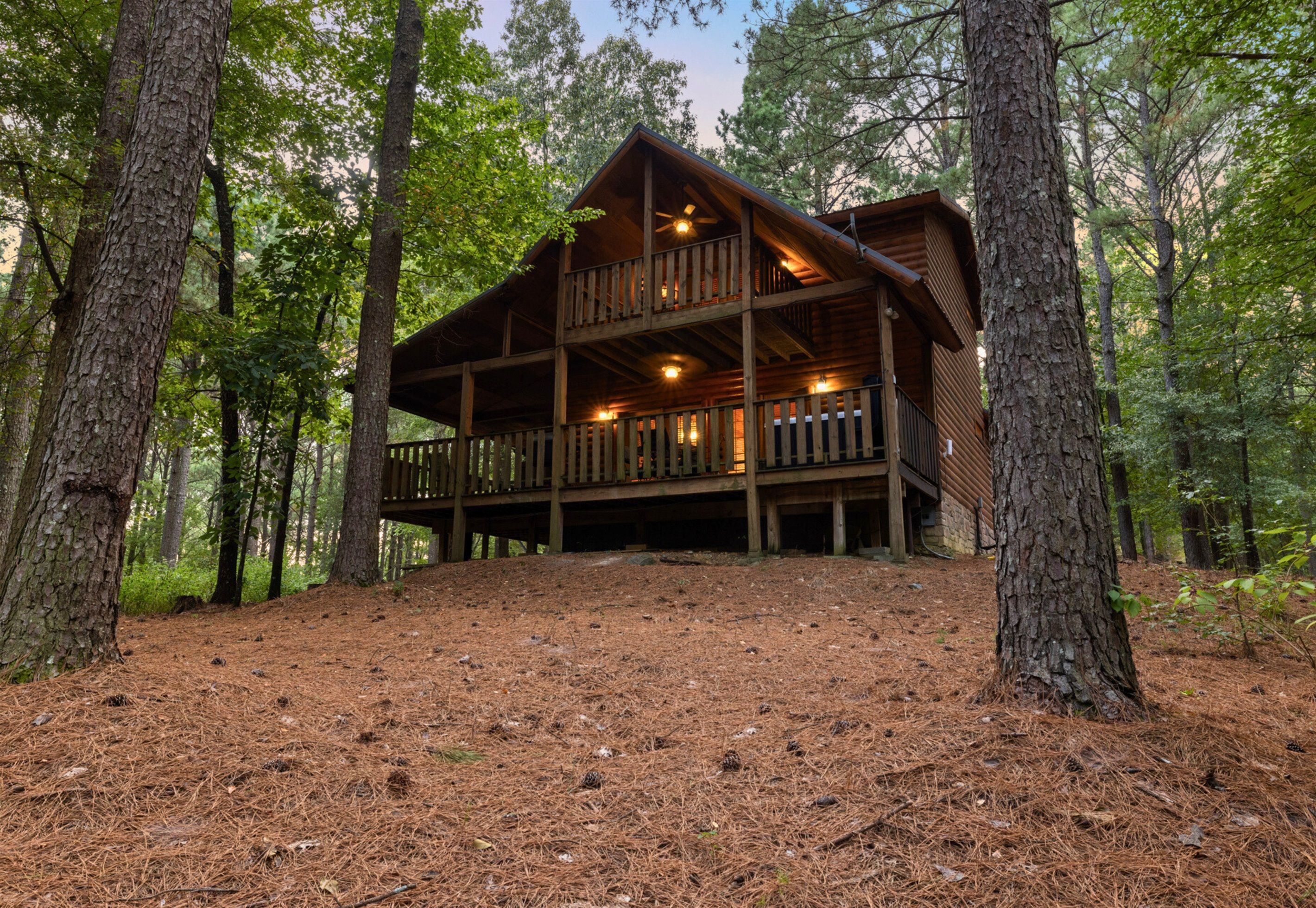 A cabin with a wooden deck and multiple levels, surrounded by trees.