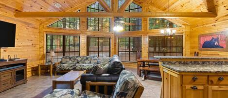 Un intérieur de cabine spacieux, doté d’un plafond haut, de grandes fenêtres, d’un coin salon confortable et d’une cuisine avec des meubles en bois.