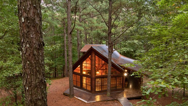 Une cabane avec un toit en pente, de grandes fenêtres et une terrasse en bois.