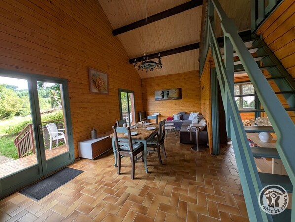 A wooden interior with a dining area, sofa, and staircase.