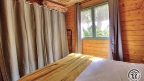 Une pièce en bois avec un lit, des rideaux et une fenêtre.