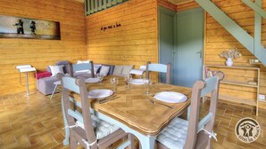 Une chaleureuse cabane en bois avec un coin repas aménagé pour quatre personnes, un escalier et un tableau accroché au mur.