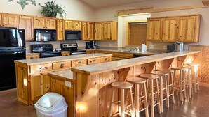 Una cucina con mobili in legno, un'isola centrale con sgabelli e un cestino.