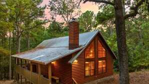 A log cabin with a wooden deck, a chimney, and a porch. - Shaui Chukka Cabin | Cozy Pondside Cabin (Broken Bow)
